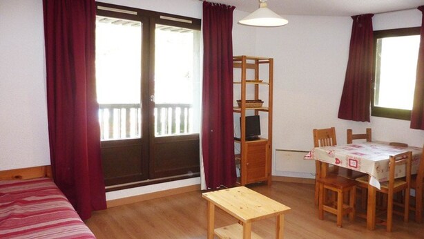 A room with a wooden bed, a small table, a dining table with chairs, and a TV on a wooden stand. - Charming studio in Les Orres for 4, ski-in/ski-out, balcony (Les Orres)