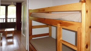 A bunk bed with a wooden frame and a mattress. - Charming studio in Les Orres for 4, ski-in/ski-out, balcony (Les Orres)