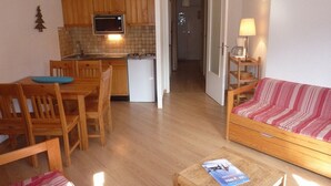 A compact living space with a kitchenette, a dining area, and a sofa. - Cozy studio, ski-in/ski-out, central location, sleeps 6, south-facing balcony (Les Orres)