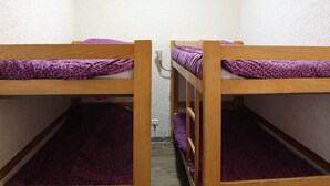 A room with two bunk beds, each with a purple patterned mattress and wooden frame.