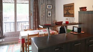 Eine kompakte Küche mit Essbereich, ausgestattet mit einem Tisch, Stühlen, einer Mikrowelle und einem kleinen Kühlschrank.