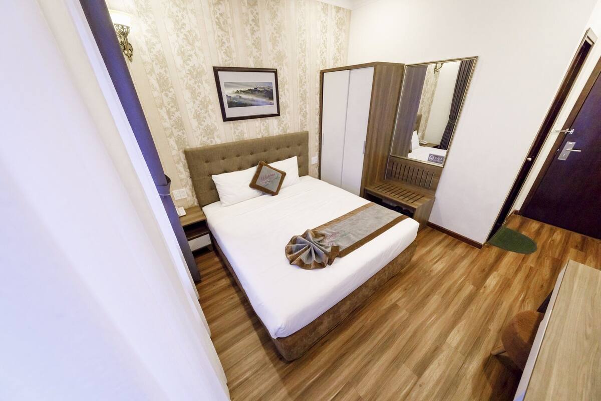 Une chambre bien rangée, avec un lit, une armoire et un miroir.