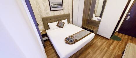 A neatly arranged bedroom with a bed, a wardrobe, and a mirror.
