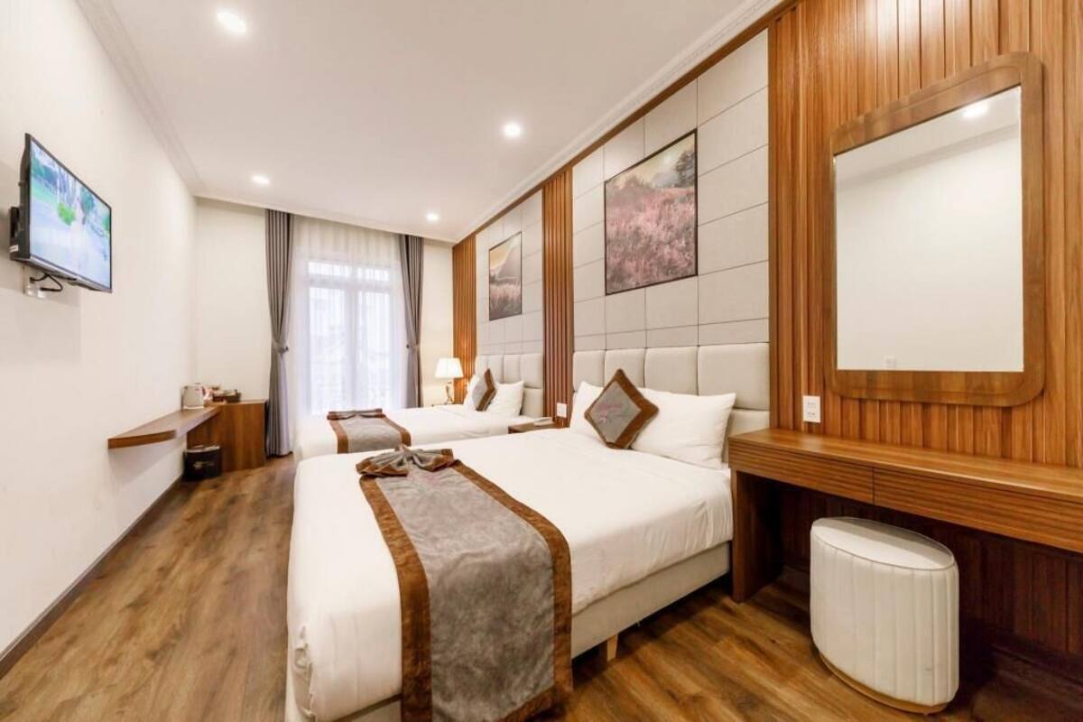 Une chambre d’hôtel avec deux lits, une télévision, un mur recouvert de panneaux en bois et un grand miroir.