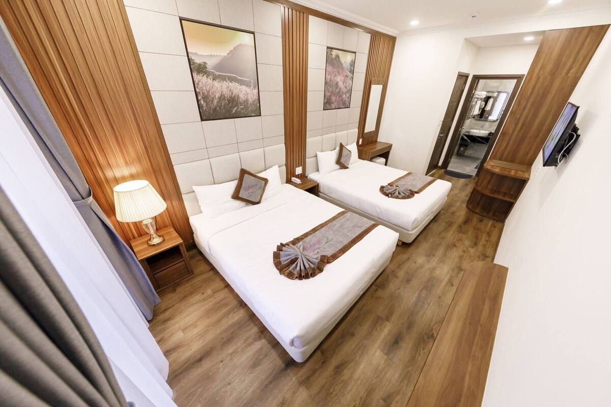 Une chambre d’hôtel avec deux lits, un plancher en bois, un grand miroir et une télévision.