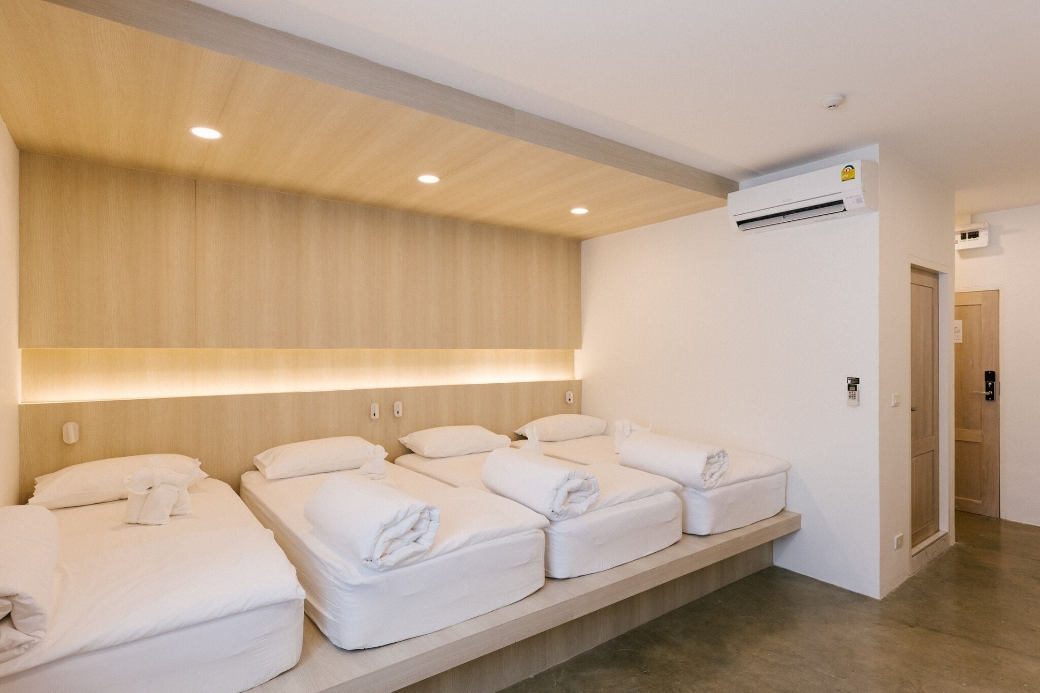 Ein Hotelzimmer mit einem Holzkopfteil, einer eingebauten Ablagefläche mit Handtüchern und einer Klimaanlage an der Wand.