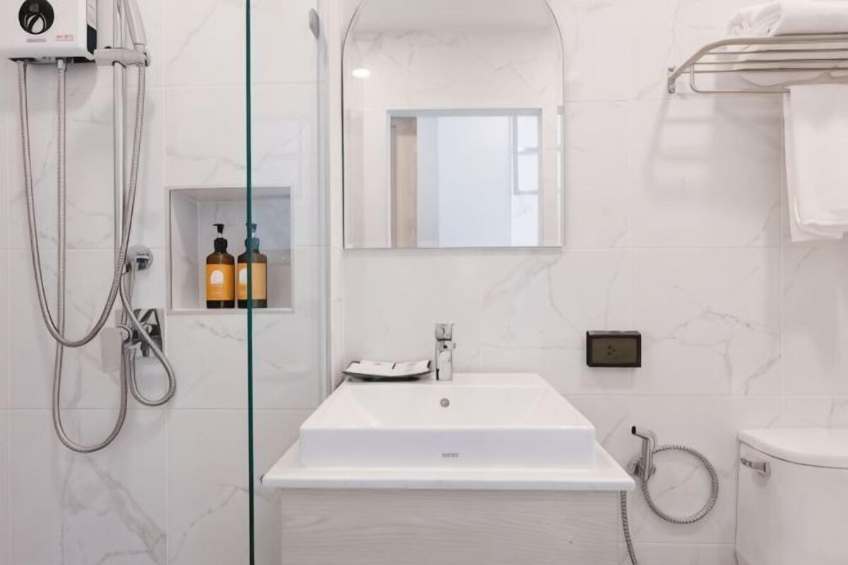 Ein Badezimmer mit einer gläsernen Duschkabine, einem weißen Waschbecken und einem Spiegel darüber.