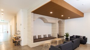 A modern reception area with a seating area, sofas, and a coffee station. - Nappiness Hotel (Bangkok)