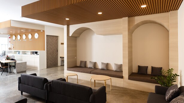A modern reception area with a wooden ceiling, seating areas, and a reception desk. - Nappiness Hotel (Bangkok)