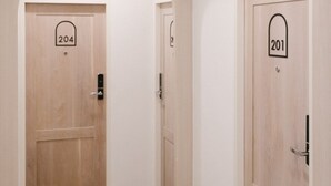 A corridor with two wooden doors labeled 204 and 201, leading to rooms. - Nappiness Hotel (Bangkok)