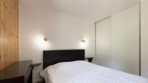 A bedroom with a bed, bedside tables, and a wardrobe. - Luxurious Ski-In/Out Apartment with Pool, Sauna & Hammam - Sleeps 4, Free WiFi, Linens Included (Les Orres)