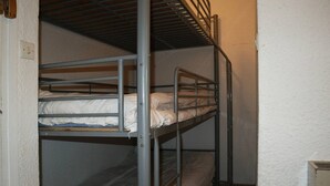 Ein Schlafraum mit Etagenbetten, Metallgeländern und einer weißen Wand.