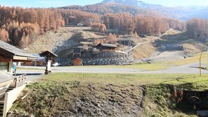 Eine Berglodge mit Stein Fundament, Holzhütten und einer Seilbahn im Hintergrund.