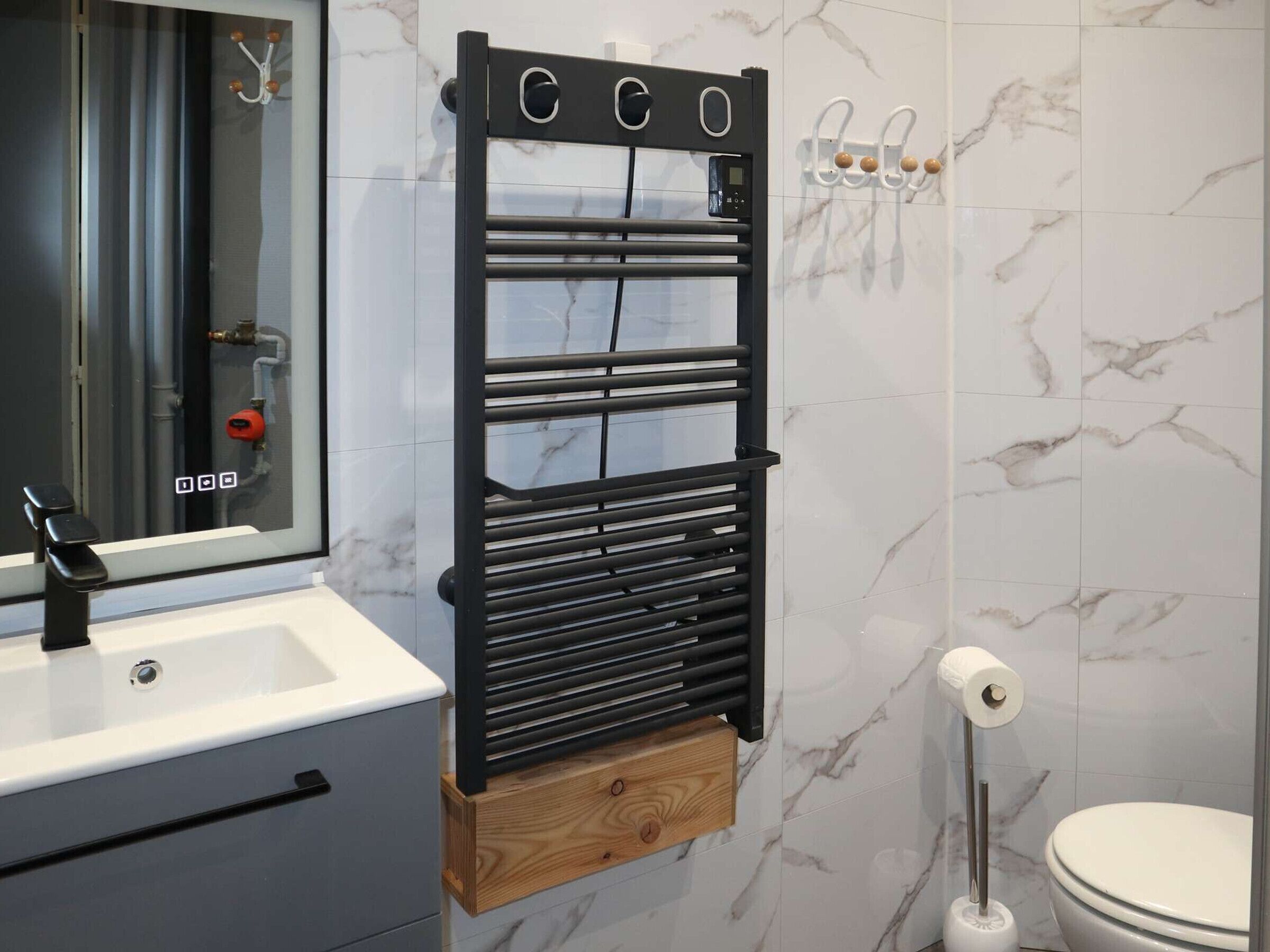 A bathroom with a black towel rack, a mirror, a sink, and a toilet.