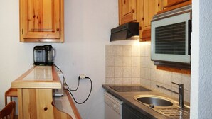 A compact kitchen with wooden cabinets, a built-in microwave, a coffee maker, and a dishwasher.