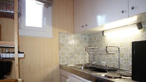 Cocina compacta con ventana, pileta, estufa y refrigerador.