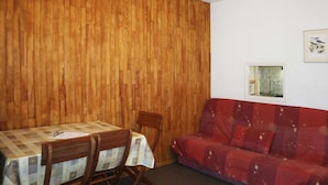 Un comedor con pared de madera, una mesa con mantel a cuadros y un sofá rojo.