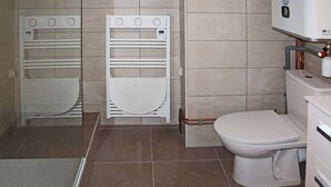 Un baño con inodoro, un lavamanos blanco y un perchero para toallas.