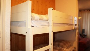 Habitación con literas, paredes de madera y una silla roja en una esquina.