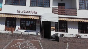 A two-story building with a sign reading "La Scardola". There are outdoor seating areas with tables and chairs, and a brick pathway leading to the entrance. - La Scardola Ristorante Hotel Bar (Baselga di Pine)