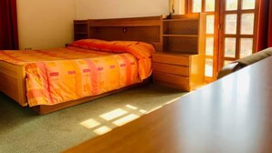 A bedroom with a bed, wooden headboard, built-in shelving, and a window with curtains. - La Scardola Ristorante Hotel Bar (Baselga di Pine)