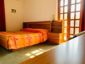 A bedroom with a bed, wooden headboard, built-in shelving, and a window with curtains. - La Scardola Ristorante Hotel Bar (Baselga di Pine)