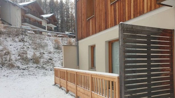 A wooden cabin with a balcony, surrounded by snow-covered ground and trees. - Spacious 3-Room Apartment for 8 with Heated Pool & Terrace in Les Orres 1800 (Les Orres)