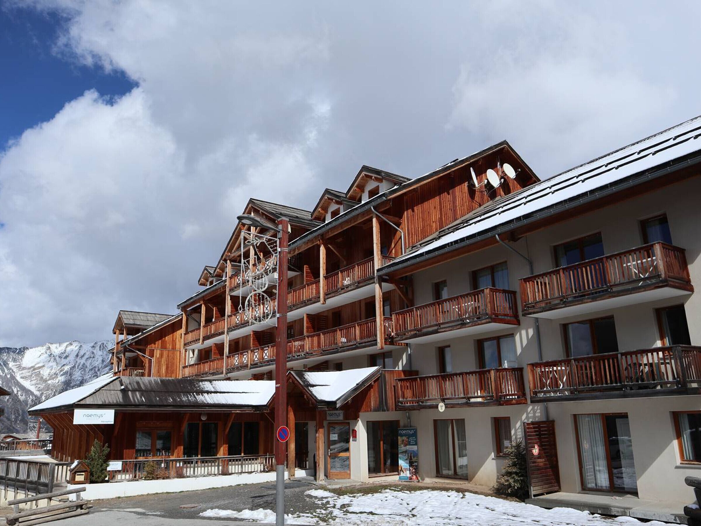 Edificio in legno a più piani con balconi, una seggiovia e un cartello con scritto 'neemys'.