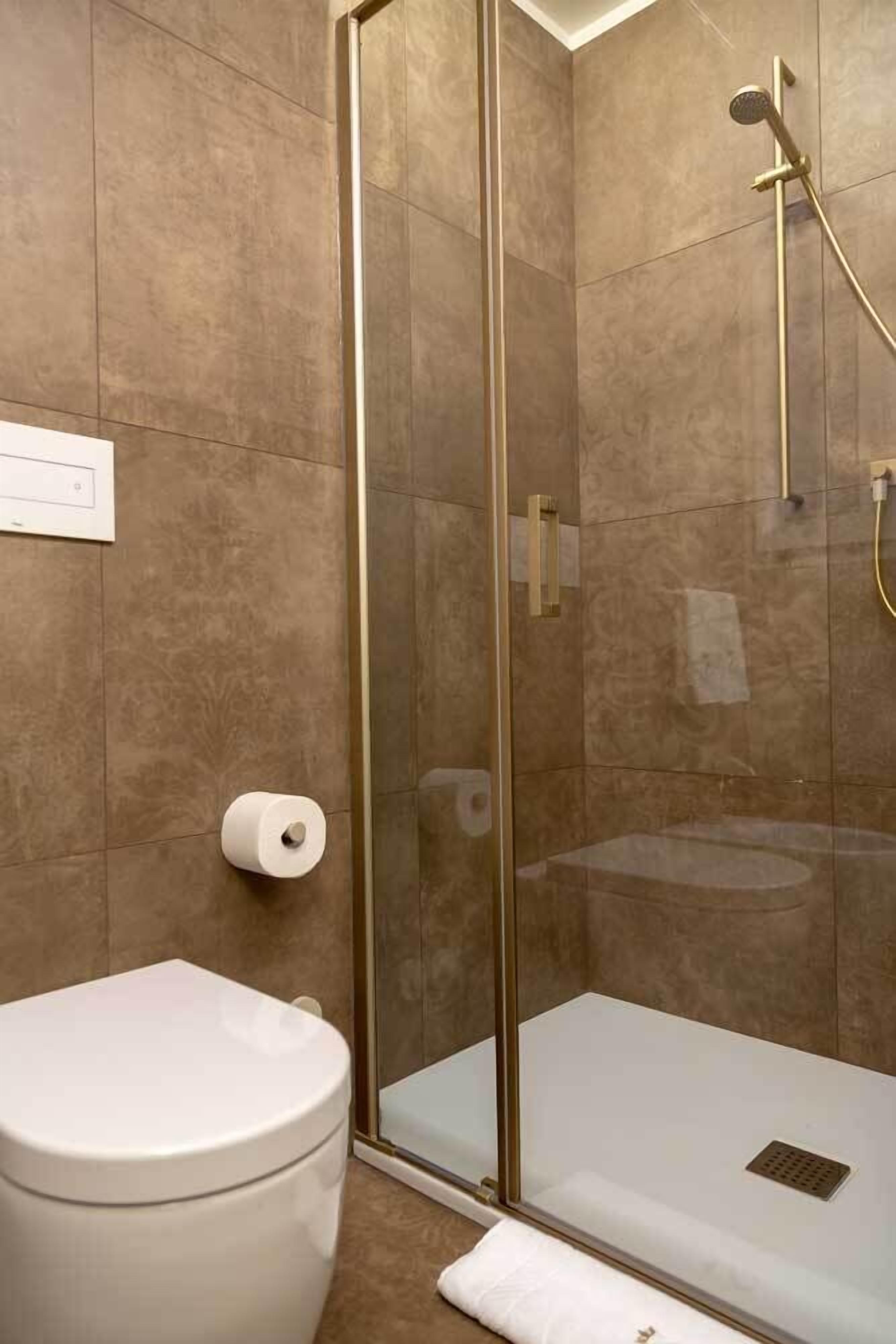 A modern bathroom with a glass-enclosed shower, a toilet, and a towel rack.