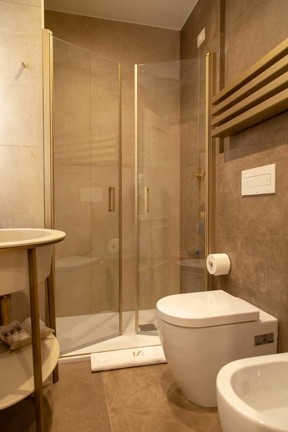 Un baño moderno con cabina de ducha de vidrio, inodoro y lavamanos.