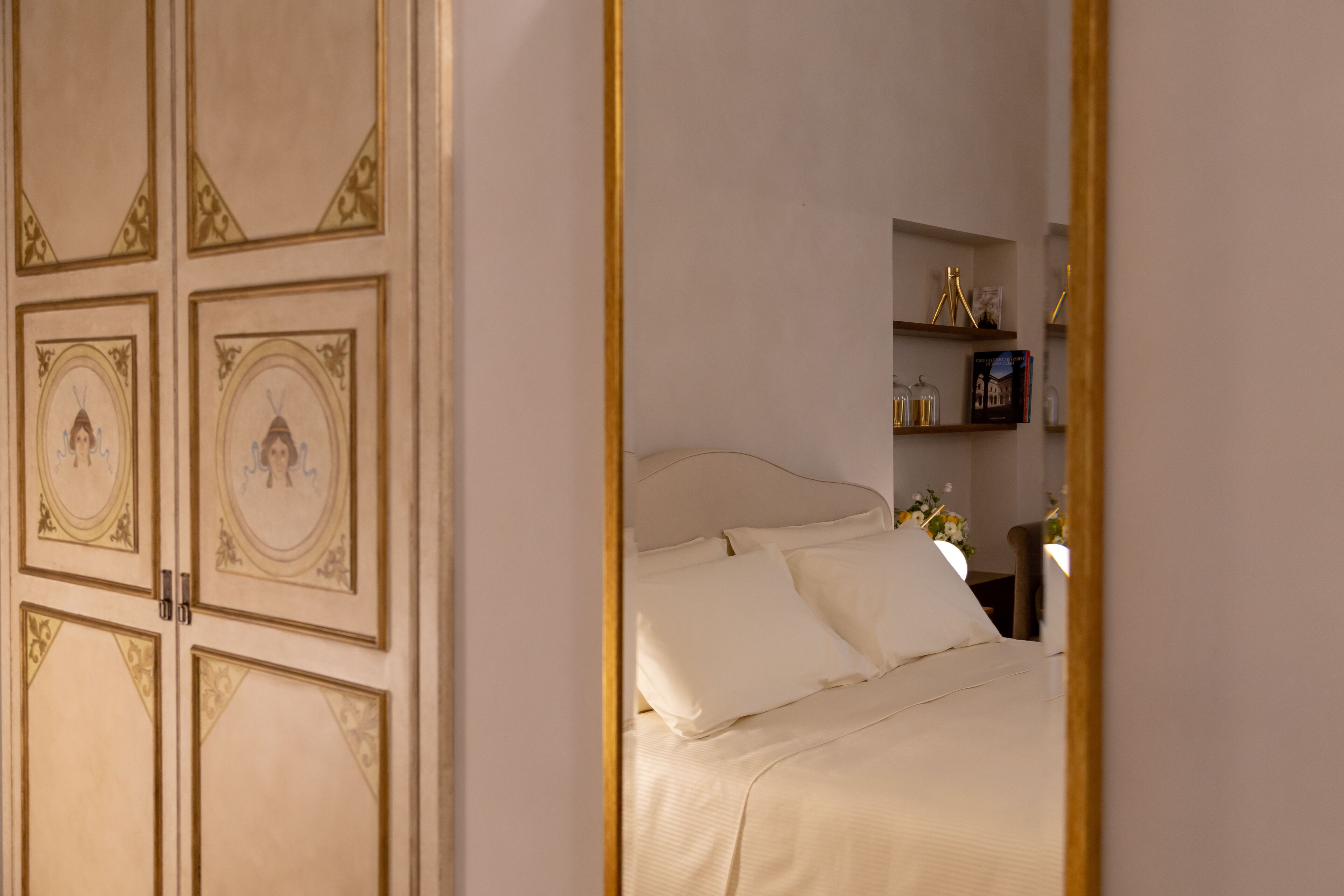 A bedroom with a bed, a nightstand, and a shelf with decorative items.