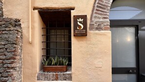 A building facade with a small window, a potted plant, and a sign with a crown symbol and text. - Dimora Storica Lo Svevo (Jesi)