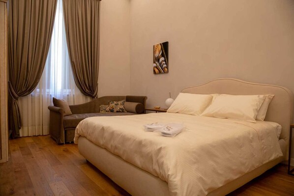 A bedroom with a large bed, a sofa, a nightstand, and a painting on the wall. - Dimora Storica Lo Svevo (Jesi)