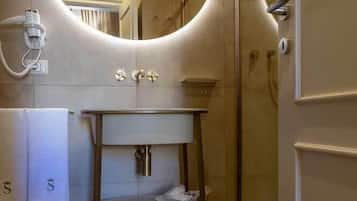 Un baño moderno con un espejo redondo, un lavabo y una ducha.