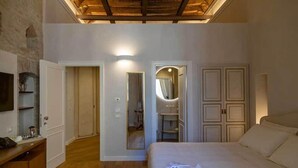 A bedroom with a wooden ceiling, a bed, a desk with a chair, a mirror, and a wardrobe. - Dimora Storica Lo Svevo (Jesi)