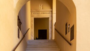 A staircase with stone steps leading up to a doorway, flanked by two walls with a decorative archway above. - Dimora Storica Lo Svevo (Jesi)