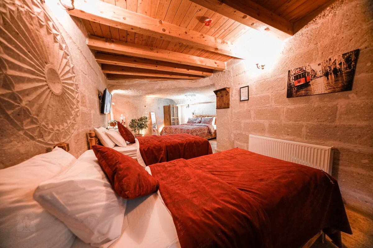 A cozy room with two beds, wooden beams, stone walls, and a vintage photo on the wall.