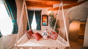 A cozy room with a macramé swing bed, a mirror, and a potted plant.