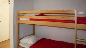 Uma cama beliche com estrutura de madeira e roupa de cama vermelha.