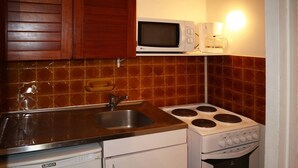 Uma cozinha compacta com pia, fogão, micro-ondas e lava-louças.