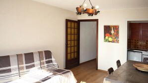 Um quarto aconchegante com sofá, mesa de jantar e cozinha.
