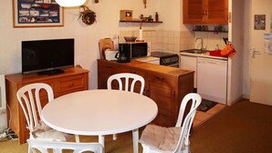 Kompakti keittiö, jossa on ruokailutila sekä televisio, kahvinkeitin ja mikroaaltouuni.