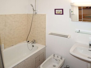 A bathroom with a bathtub, a small sink, and a bidet.