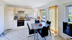 Una cocina compacta con comedor, horno integrado y un amplio ventanal con cortinas.