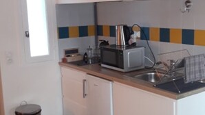 A compact kitchen with a microwave, sink, and a trash bin. - ScandiChic De La Gare Studio (Arles)