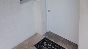 A white door with a handle and a keyhole, a small window above it, and a metal grate on the floor. - ScandiChic De La Gare Studio (Arles)