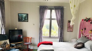 A bedroom with a bed, a chair, a TV, and a window with curtains. - 2-bed Apartment Overlooking the River (Avesta)