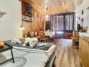 Quarto aconchegante com cama, área de jantar e teto de madeira.