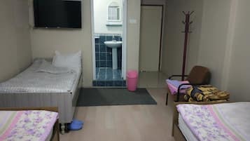 Habitación de hotel con dos camas, televisor, baño visible a través de una puerta abierta, perchero y una silla.
