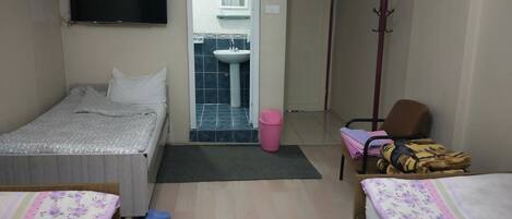 A hotel room with two beds, a television, a bathroom visible through an open door, a coat rack, and a chair.